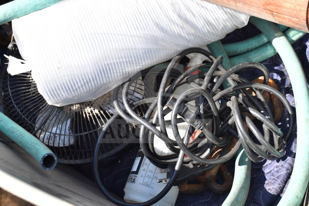 Pallet lot with assorted items including a fan, coiled cords, a white utility container, and hoses, in used condition.