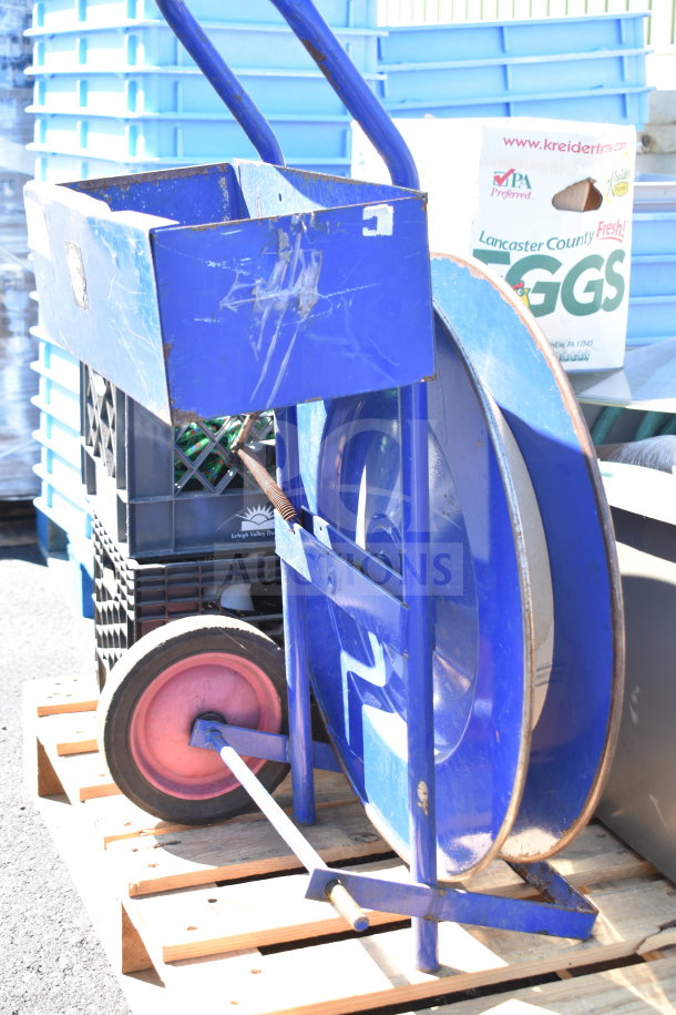 Pallet lot featuring a blue banding station with wheels, cords, and additional items, in used condition.