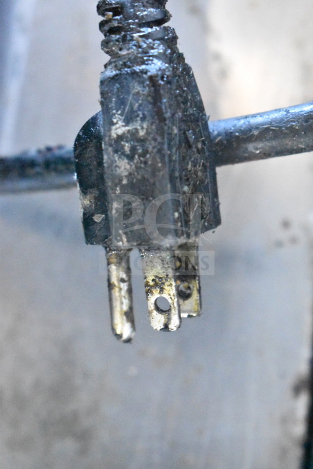 A close-up of a worn electrical plug with visible dirt and corrosion, connected to a cord.