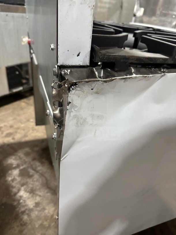 Scratched side of a brand new Kutano 6-burner range/oven combo, model KUT6BRN36N6, with visible dents on stainless steel.