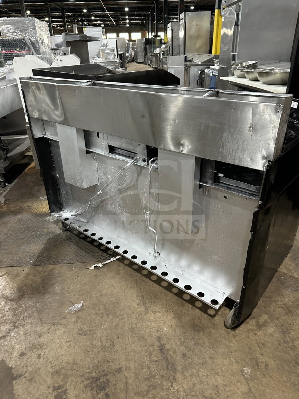 Garland commercial stainless steel range with 6 burners, griddle, double ovens, broiler, backsplash, on casters, back view.