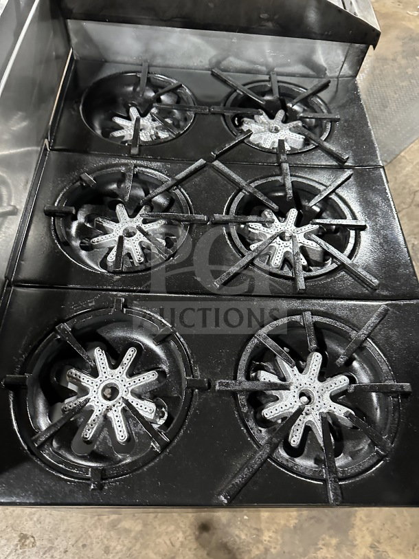 Garland commercial stainless steel 6 burner range with split top, griddle, double ovens, broiler, and salamander shelf.
