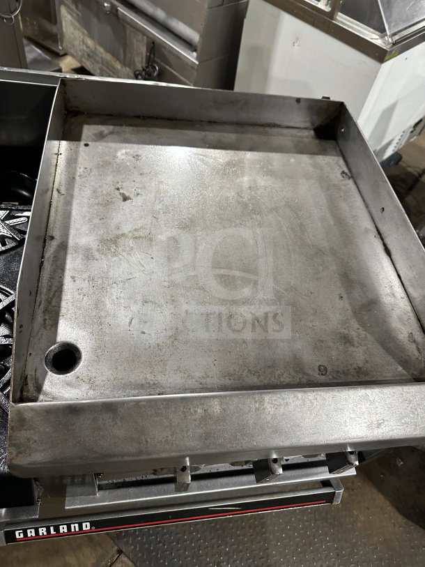 Garland stainless steel 6 burner range with raised flat griddle and oven combo, including broiler and salamander shelf.