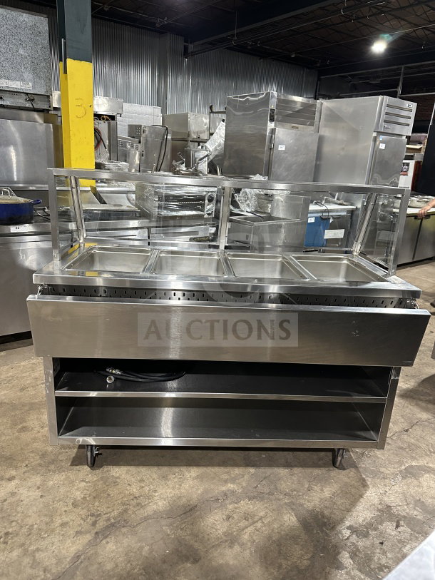 Randell stainless steel 4-well electric steam table, Model RANHTD4S. Features sneeze guard, 2-shelf storage, casters, 120V.