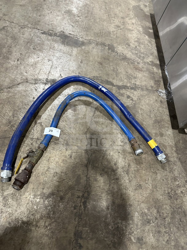 Dormont blue commercial gas connector hoses on concrete floor, showing wear. Features fittings and visible label with number 20.