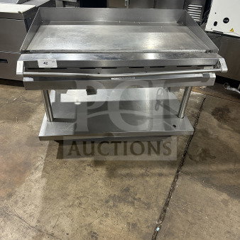 Commercial stainless steel griddle with cheese melter and overfire broiler on casters, item 42, in used condition.