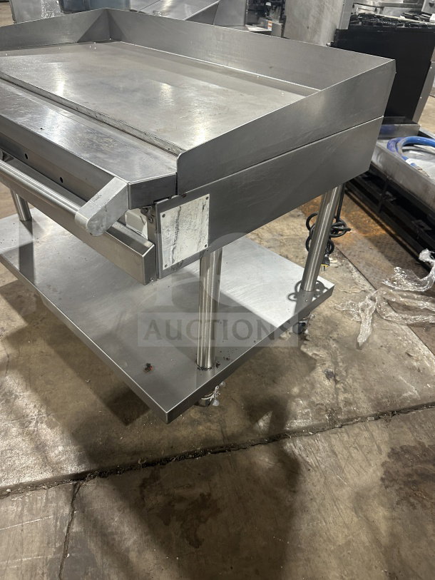 Stainless steel commercial griddle and cheese melter with overfire broiler, featuring casters for mobility. In good condition.