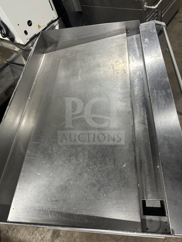 Commercial stainless steel griddle with cheese melter and overfire broiler, on casters, in good condition.