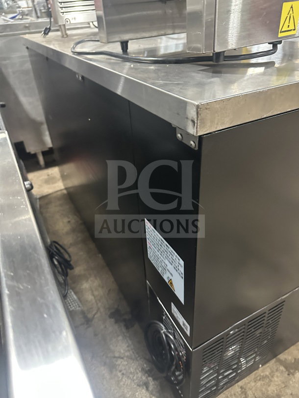 Black commercial back bar refrigerator with poly-coated wire rack, featuring two sliding glass doors. Visible label with specifications.