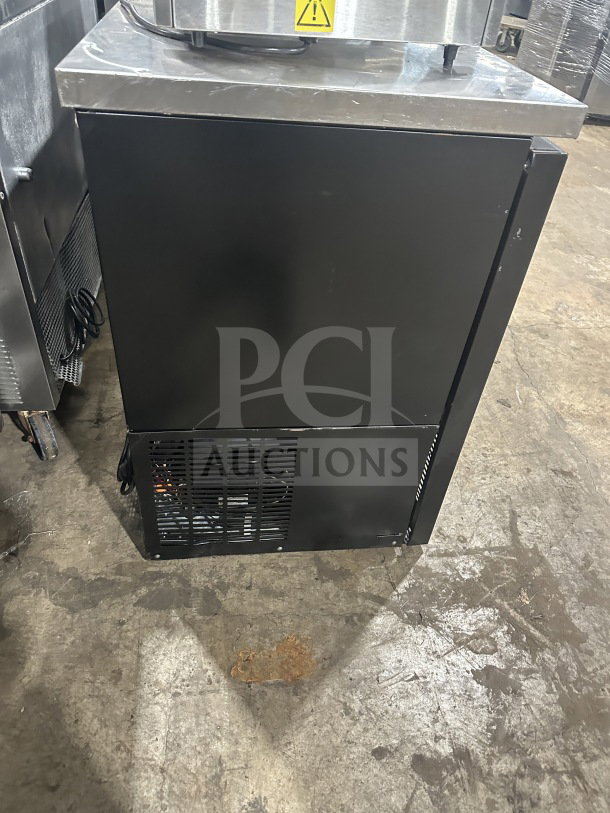 Black commercial back bar refrigerator with poly-coated wire rack and two sliding glass doors, in good condition.