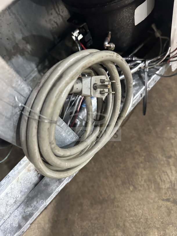 Coiled power cord of Turbo Air M3 Series MUR-72 commercial refrigerator, showing metal base and wiring setup.