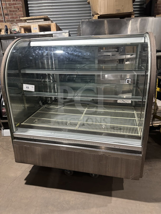 Commercial stainless steel refrigerated bakery display case with curved glass, three tiers, rear sliding glass door, and poly-coated wire rack.