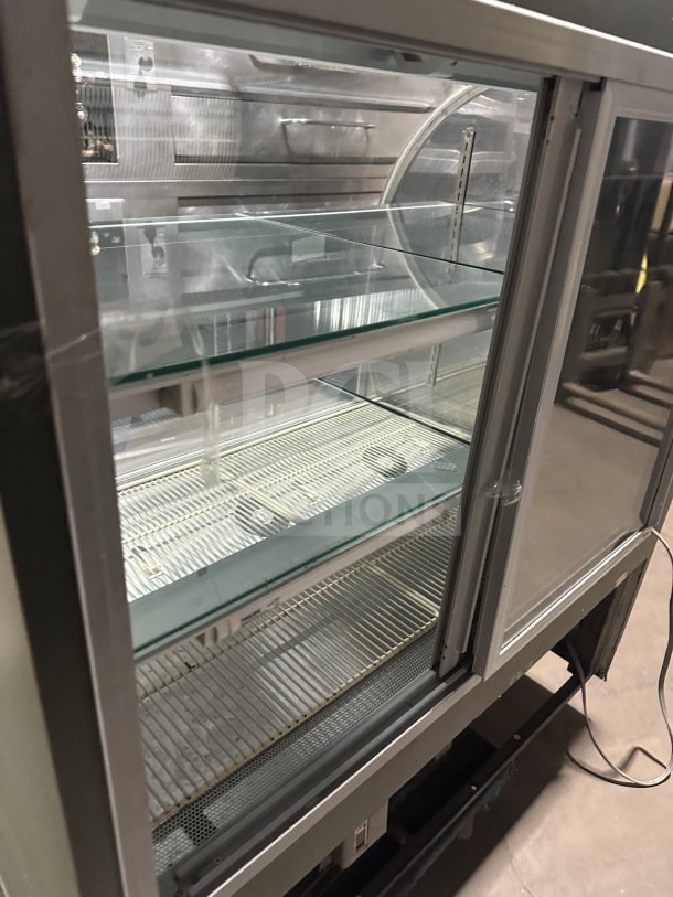 Commercial stainless steel 3-tier bakery display case with curved glass, rear sliding glass door, and poly-coated wire racks.