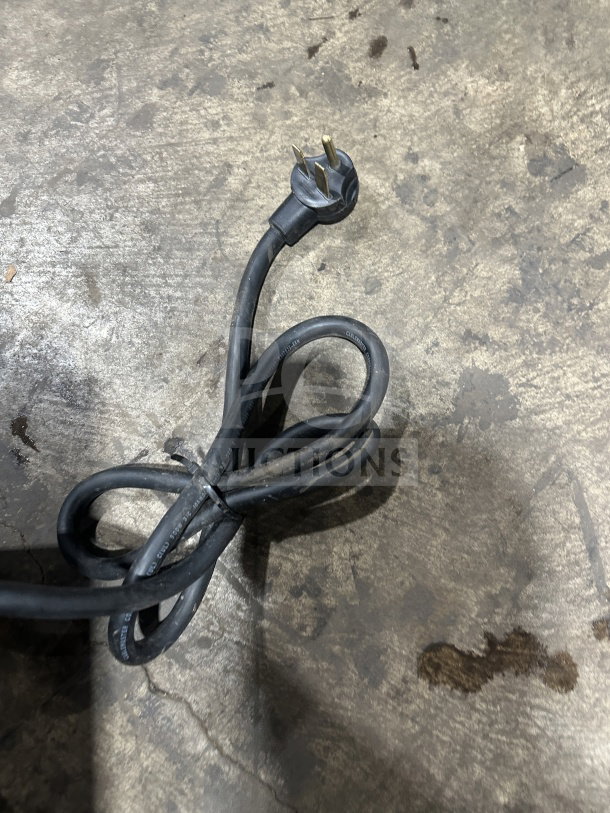 TurboChef NGO commercial oven power cord. Black cord with three-prong plug on concrete floor.