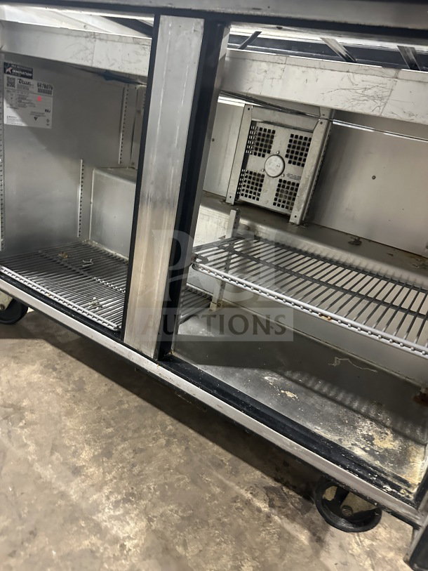 True TSSU-48-18M-B-HC stainless steel 2-door prep table with poly-coated wire rack, on casters, moderate wear.