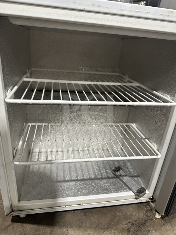 Commercial countertop display cooler with single glass door, poly-coated wired racks, and legs. Good condition.