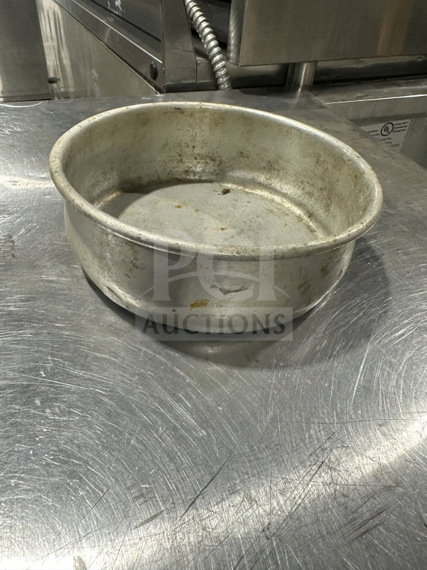 Stainless steel deep-dish pizza pan with slight wear, commercial-grade. Ideal for baking, enhancing kitchen utility.