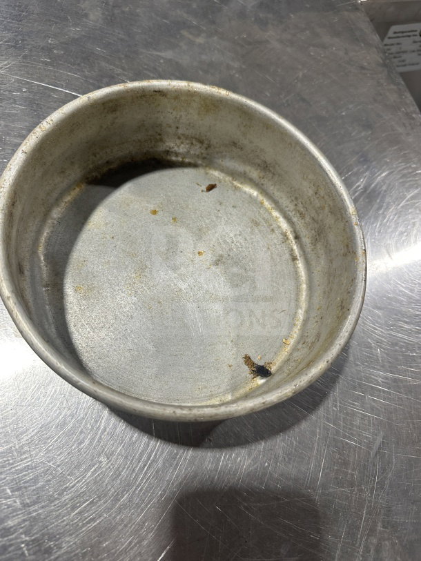 Commercial stainless steel deep-dish pizza pan, used condition, visible wear marks, ideal for dough preparation.