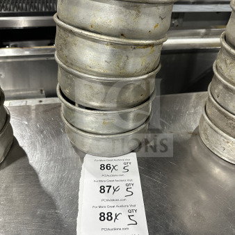 Stainless steel deep-dish pizza pans, stacked, showing signs of use. Auction tags indicate quantities of 5 per lot.