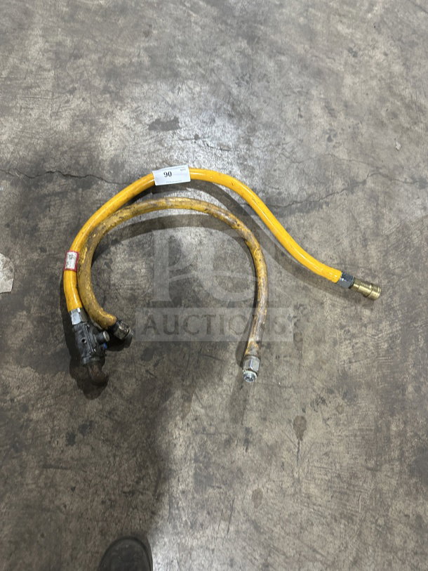 Yellow commercial gas connector hose, used, with fittings and visible labels; moderate wear indicates prior use.