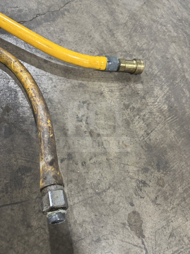 Yellow commercial gas connector hose with metal fittings, in good condition, slight wear visible on surface.