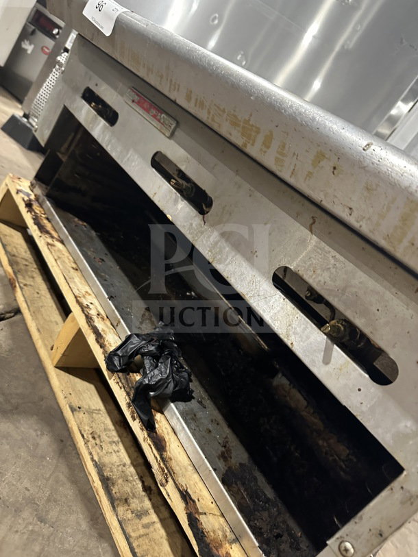 American Range commercial stainless steel flat griddle, natural gas powered, with back and side splash, on wooden pallet.