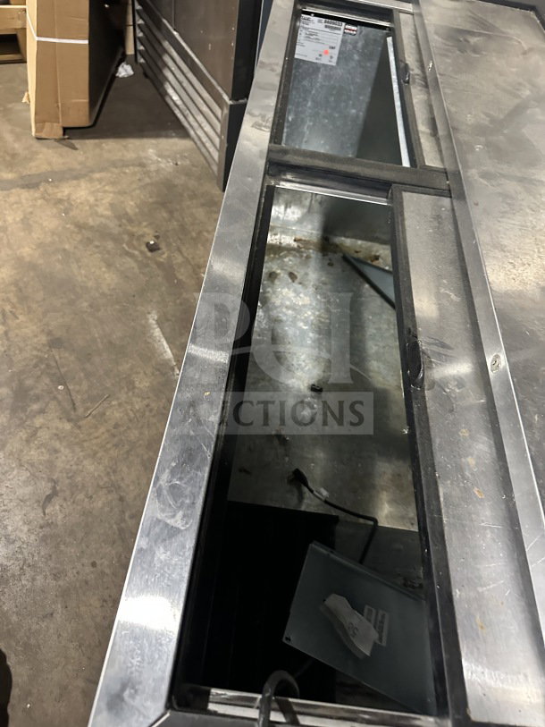 True commercial black horizontal forced air bottle cooler with stainless steel worktop and dual easy-slide access lid.