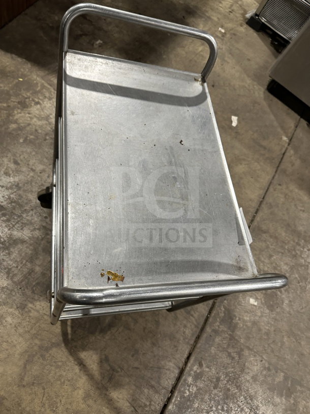 Commercial stainless steel 3-shelf utility cart in good condition. Features sturdy legs and handles. Slight wear visible.