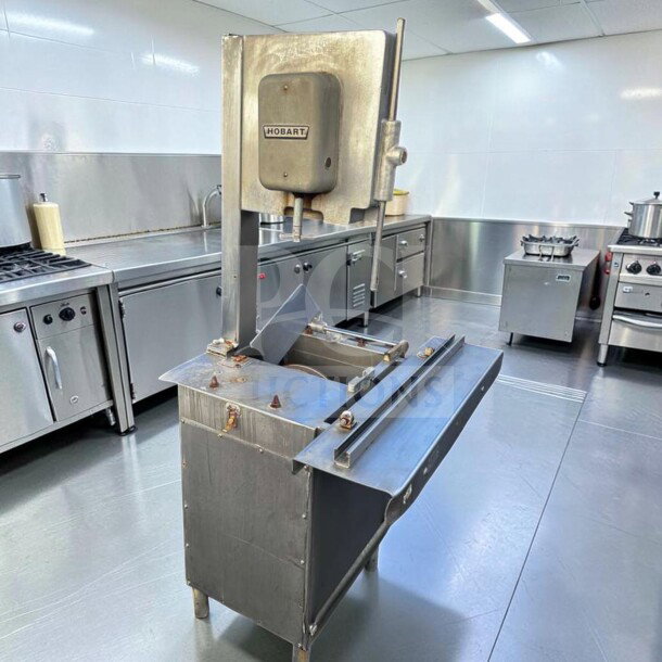 Hobart 5614 commercial meat saw, 2 HP, 3 phase, heavy-duty, used condition, labeled "Hobart," in a commercial kitchen. For parts or repair.