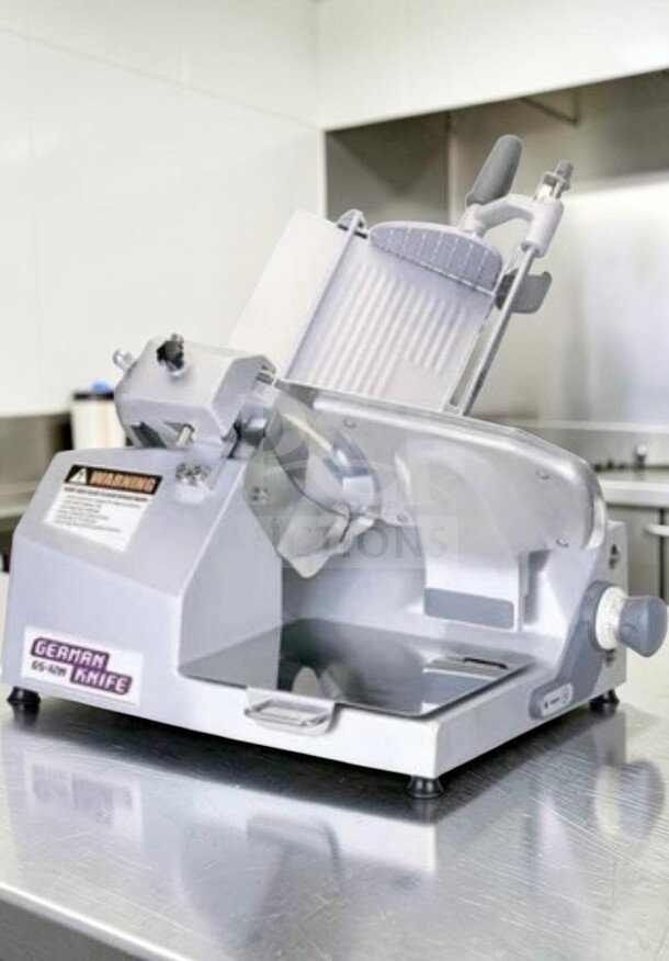 German Knife GS-12M 12" slicer in excellent condition. Features gravity feed, 1/2 HP motor, fully operational. Labels: model and warning.