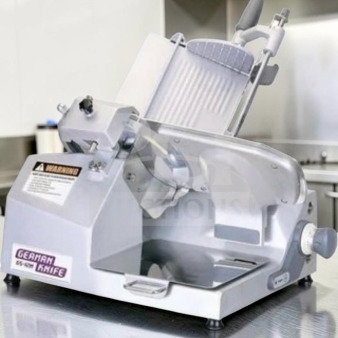 German Knife GS-12M 12" slicer in excellent condition. Features gravity feed, 1/2 HP motor, fully operational. Labels: model and warning.