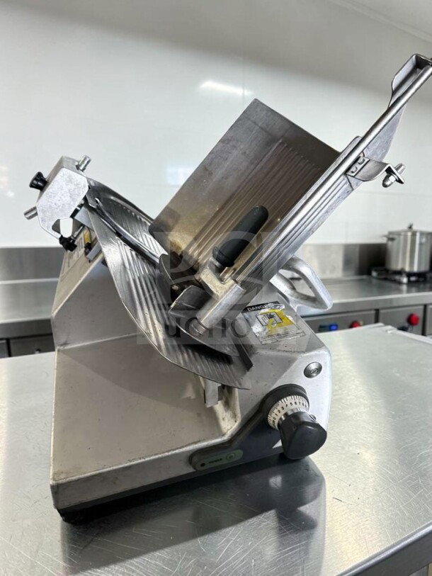 German Knife GS-12M 12" slicer, gravity feed, 1/2 HP, excellent condition, fully tested, labeled with safety warning.