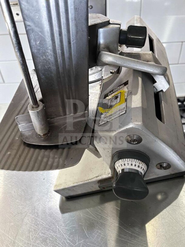 German Knife GS-12M slicer, 12" blade, heavy-duty gravity feed, 1/2 HP. Fully operational, excellent condition, visible safety label.