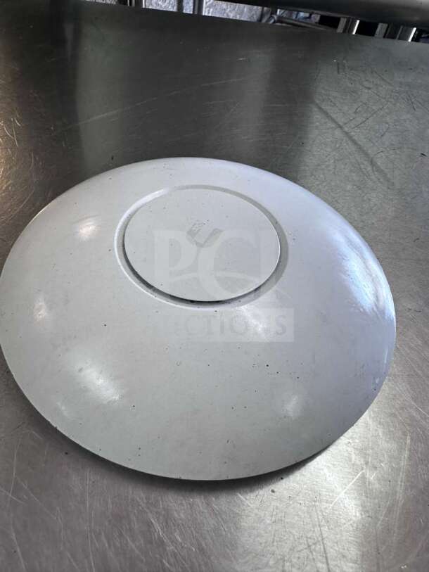 Ubiquiti UniFi UAP-AC-PRO wireless access point, dual band, 1750 Mbps, superior condition, on metallic surface.