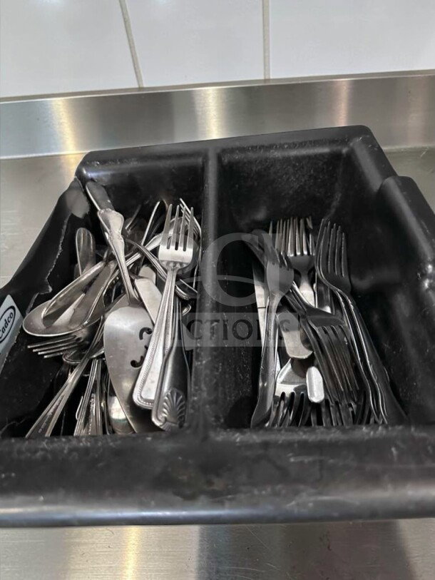 Commercial stainless steel flatware lot in exceptional condition, featuring mixed pattern forks and spoons in a black container.