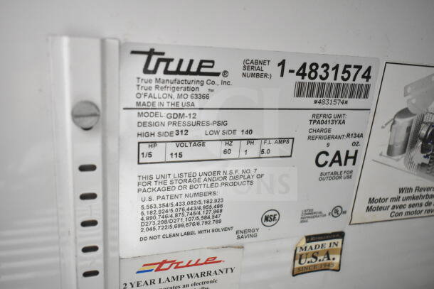 True GDM-12 Commercial Cooler, 115V, single door, NSF certified, label indicates model details and refrigerant info.