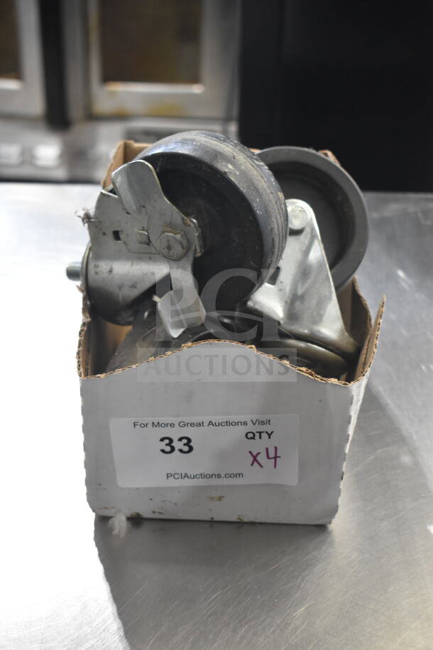Lot of 4 commercial casters in a box. Includes wheel locks. Label indicates item number 33, quantity 4. Good condition.