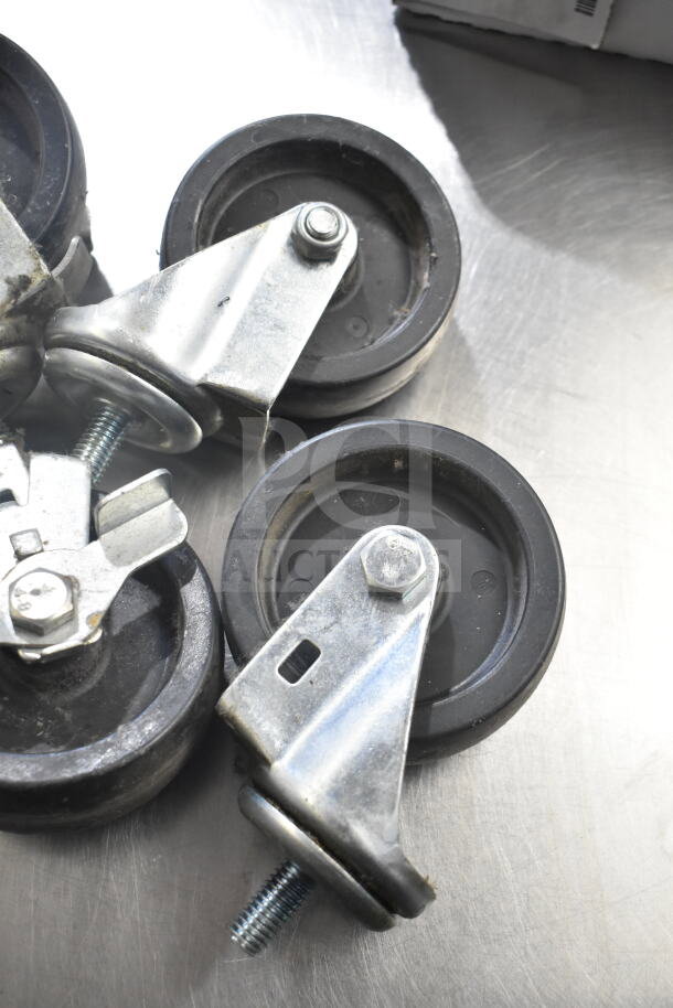 Lot of 4 commercial casters, black wheels, metal frames, in good condition. Ideal for heavy-duty furniture or equipment.