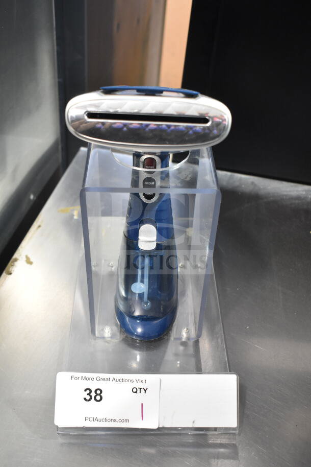 Blue handheld steamer in stand, features turbo and steam settings. Auction tag number 38 visible.