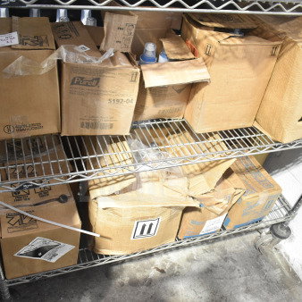 Lot of boxes on metal shelf including Purell Hand Sanitizer cartons, labels visible. Various items, mixed condition.