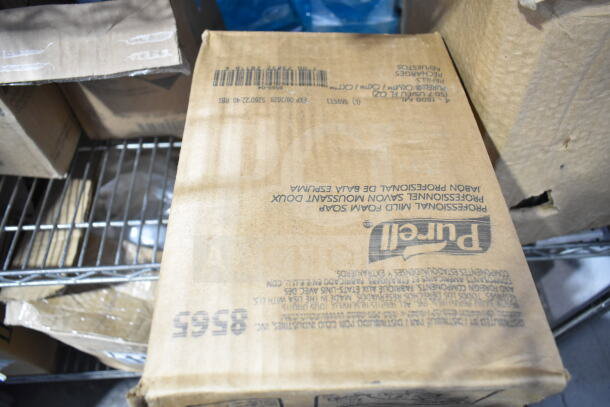 Lot of various items including a sealed box of Purell professional hand sanitizer. Boxes are stacked on a metal shelf.