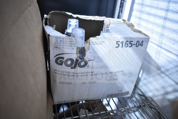 Box of GoJo Green Certified Foam Hand Cleaner bottles, expiration 10/2028, partially torn packaging, stored on metal shelf.