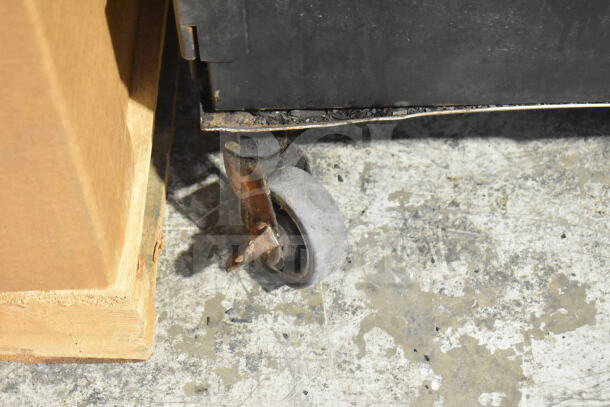 CookShack 250 Commercial Electric Smoker Cabinet wheel, showing wear and rust. 208 volts, black exterior.