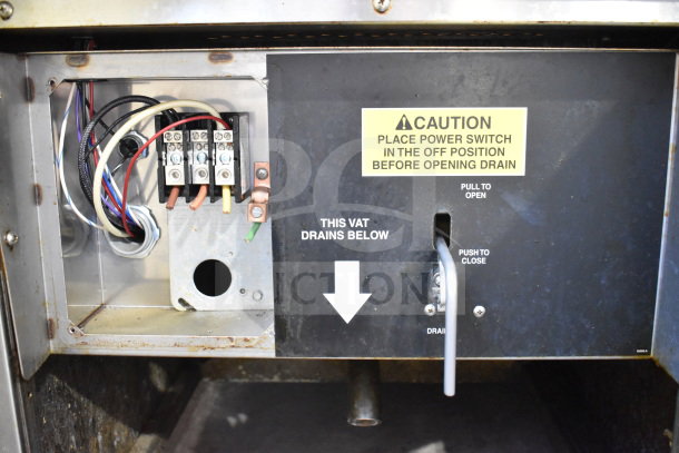 Stainless steel Giles EOF-24 commercial fryer interior showing voltage connections and warning labels for safe operation.