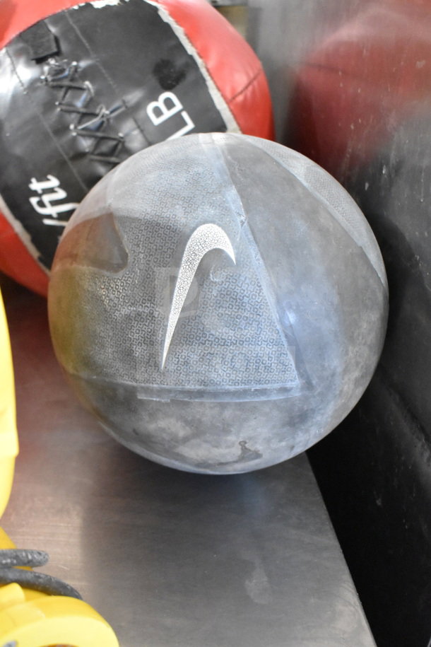 Gray sports ball with Nike logo, 20 lb label visible. Red and black punching bag marked "20 LB" nearby.