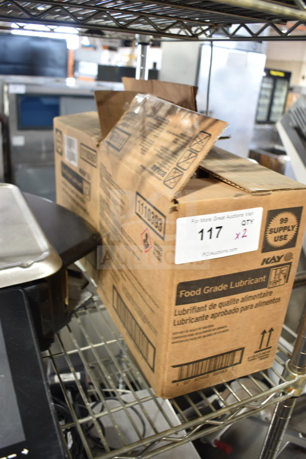 Two boxes of Kay food grade lubricant on a metal shelf. Label indicates auction lot number 117, quantity 2.