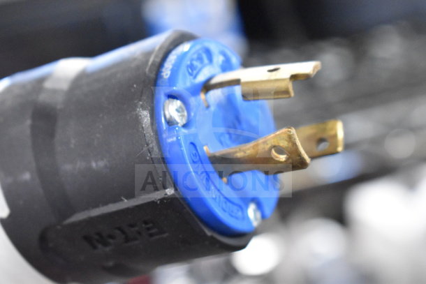 Close-up of a blue and black power plug, possibly for a Countertop 3 Well Steam Table. Shows metallic prongs and screws.