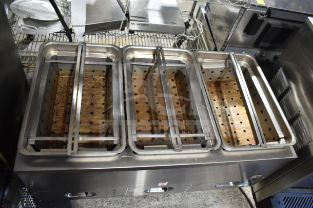 Stainless steel countertop 3 well steam table with perforated trays, showing signs of wear, ideal for food service use.