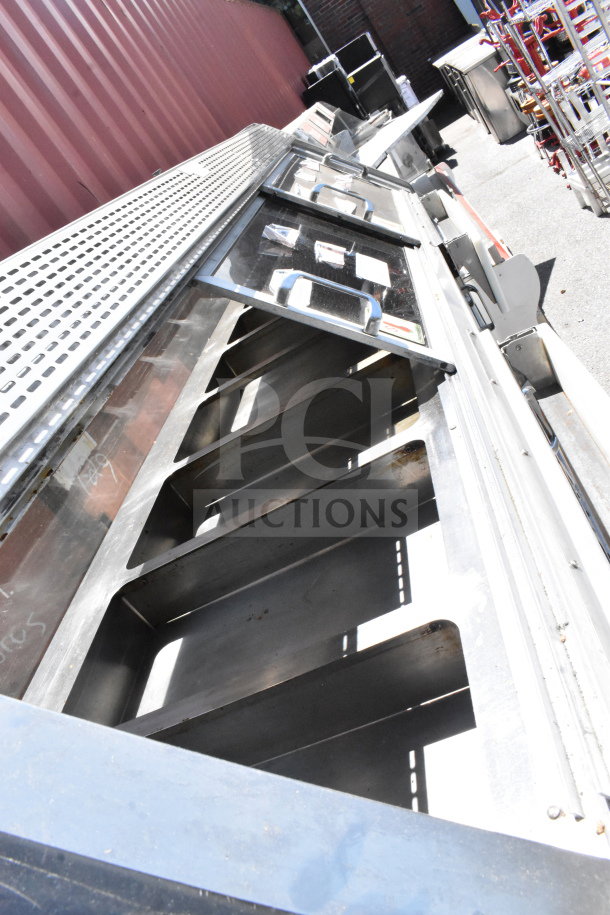 Commercial floor-style warming display case merchandiser, stainless steel, multiple clear doors, outdoor setting.