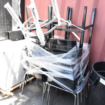 Stack of 11 dining height chairs wrapped in plastic, with metal legs and black seats, in good condition.